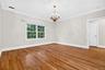 Hardwood flooring, crown molding, double-pane window, and a central chandelier