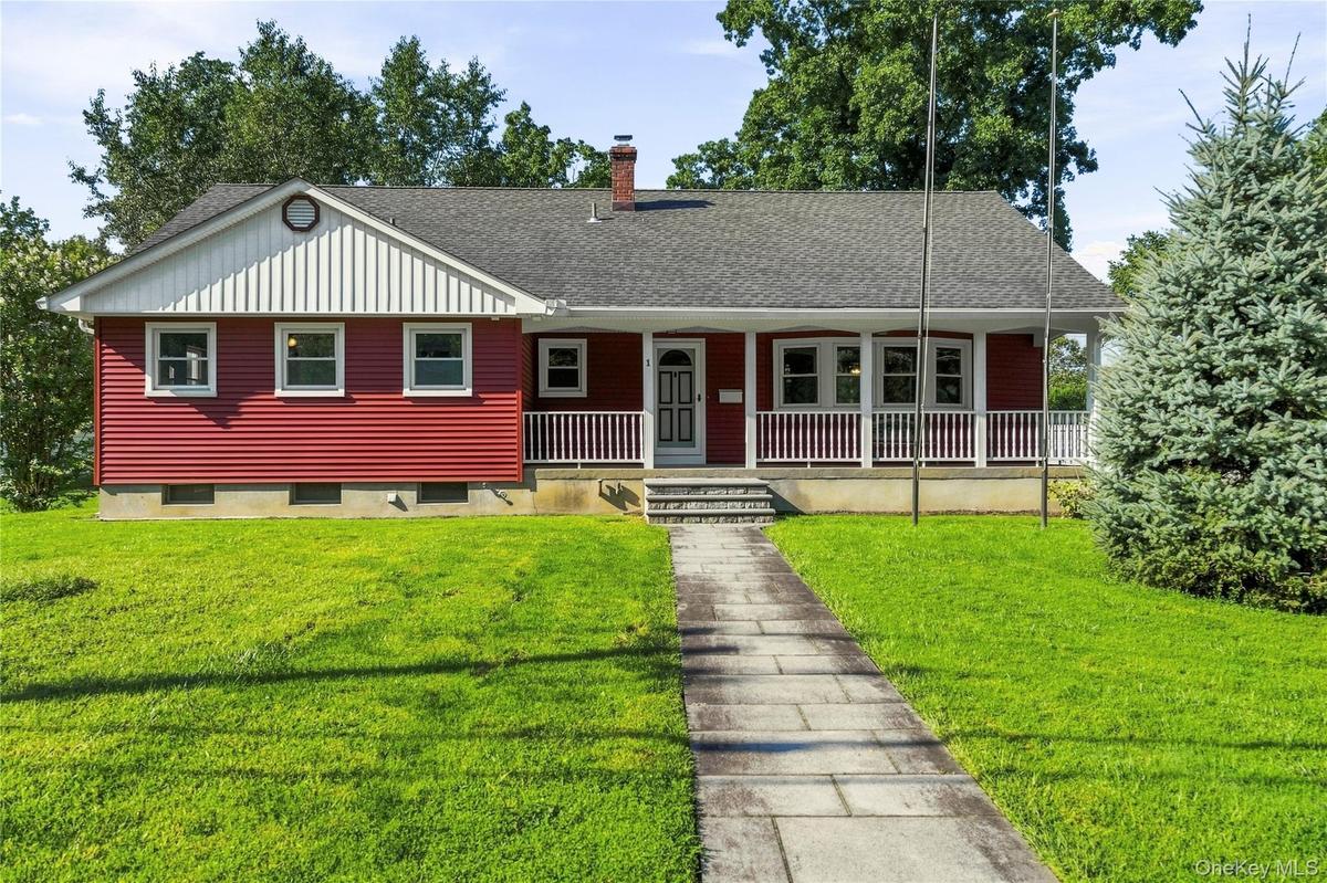 Red-sided residence featuring a covered front porch with white railings, a front-facing gable with vertical siding, and a stone-paved walkway