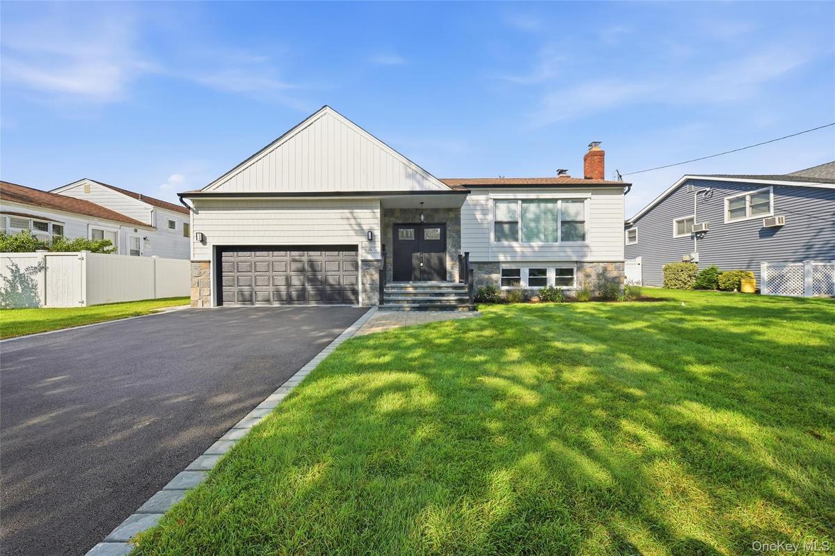 Contemporary exterior with a stone facade, a two-car garage, and a paved driveway