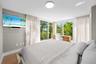Primary bedroom with large windows, wood floors, and serene ambiance — bright retreat in South of Fifth neighborhood.