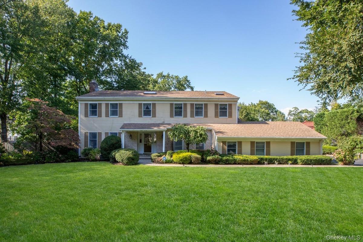 Colonial inspired home featuring a front lawn, a porch, and a chimney