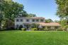 Colonial inspired home featuring a front lawn, a porch, and a chimney