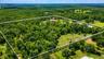 Stunning aerial perspective showcasing over 24 acres of usable land, offering privacy, expansion potential, and multiple structures including the resi