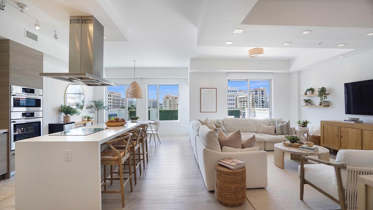 An open composition of living, dining and kitchen spaces, framed by natural light and the terrace beyond.