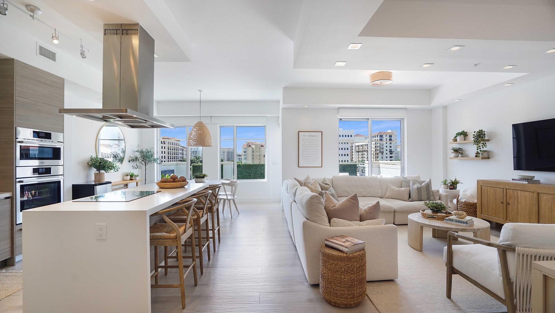 An open composition of living, dining and kitchen spaces, framed by natural light and the terrace beyond.