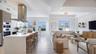An open composition of living, dining and kitchen spaces, framed by natural light and the terrace beyond.