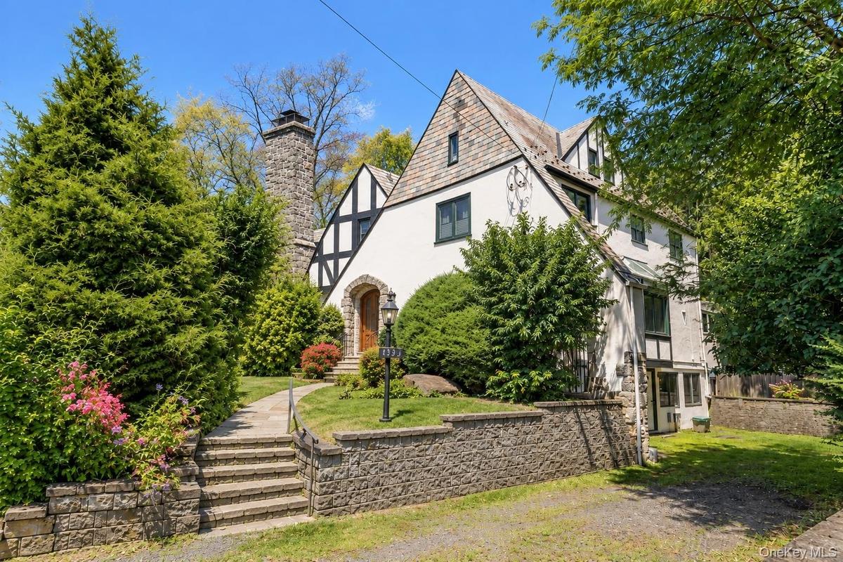 The 1929 Stockbroker Tudor reveals another side of its character—steep gables, a substantial stone chimney, slate roof and mature landscaping frame th