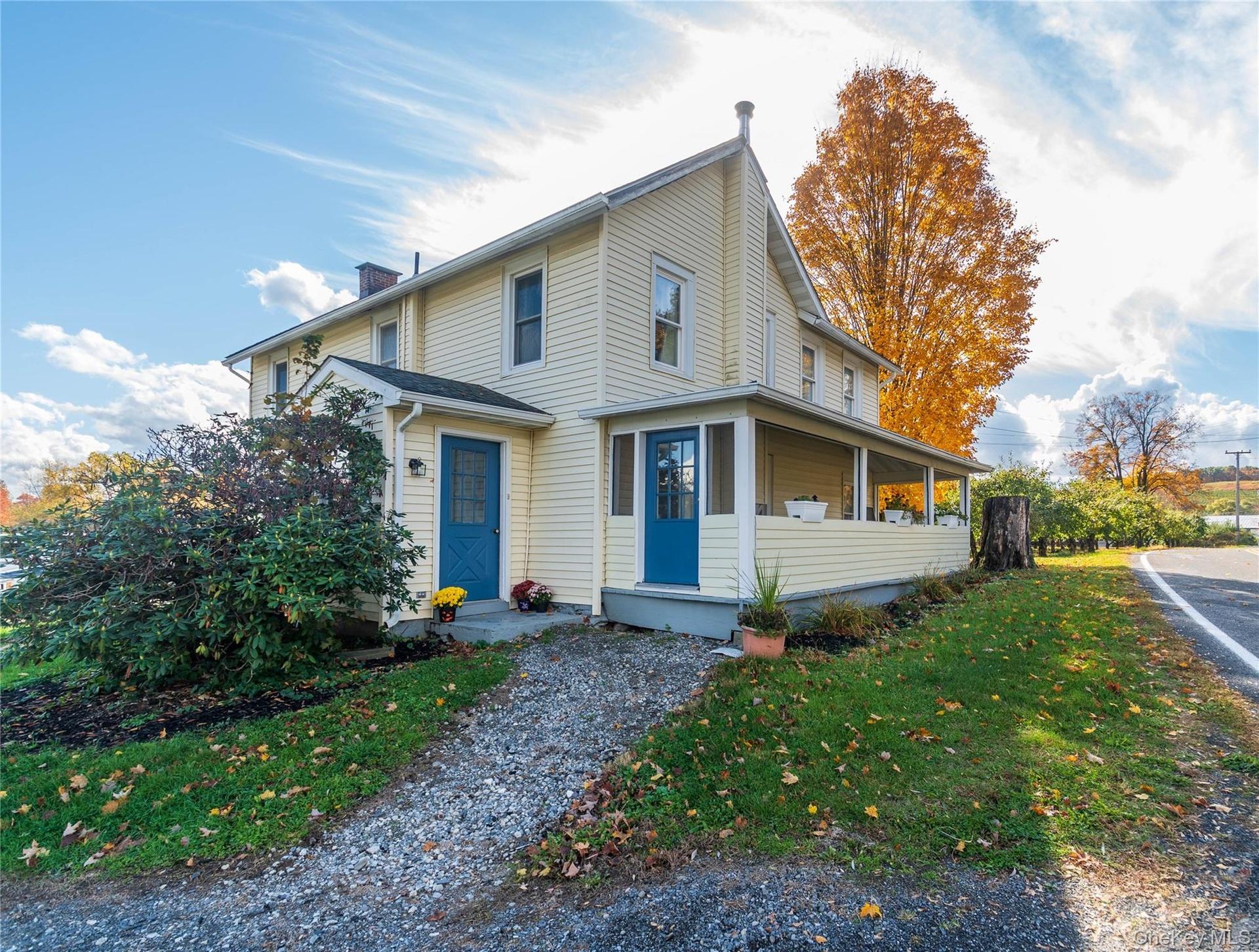 View of front of property with a chimney, a front yard, and a porch