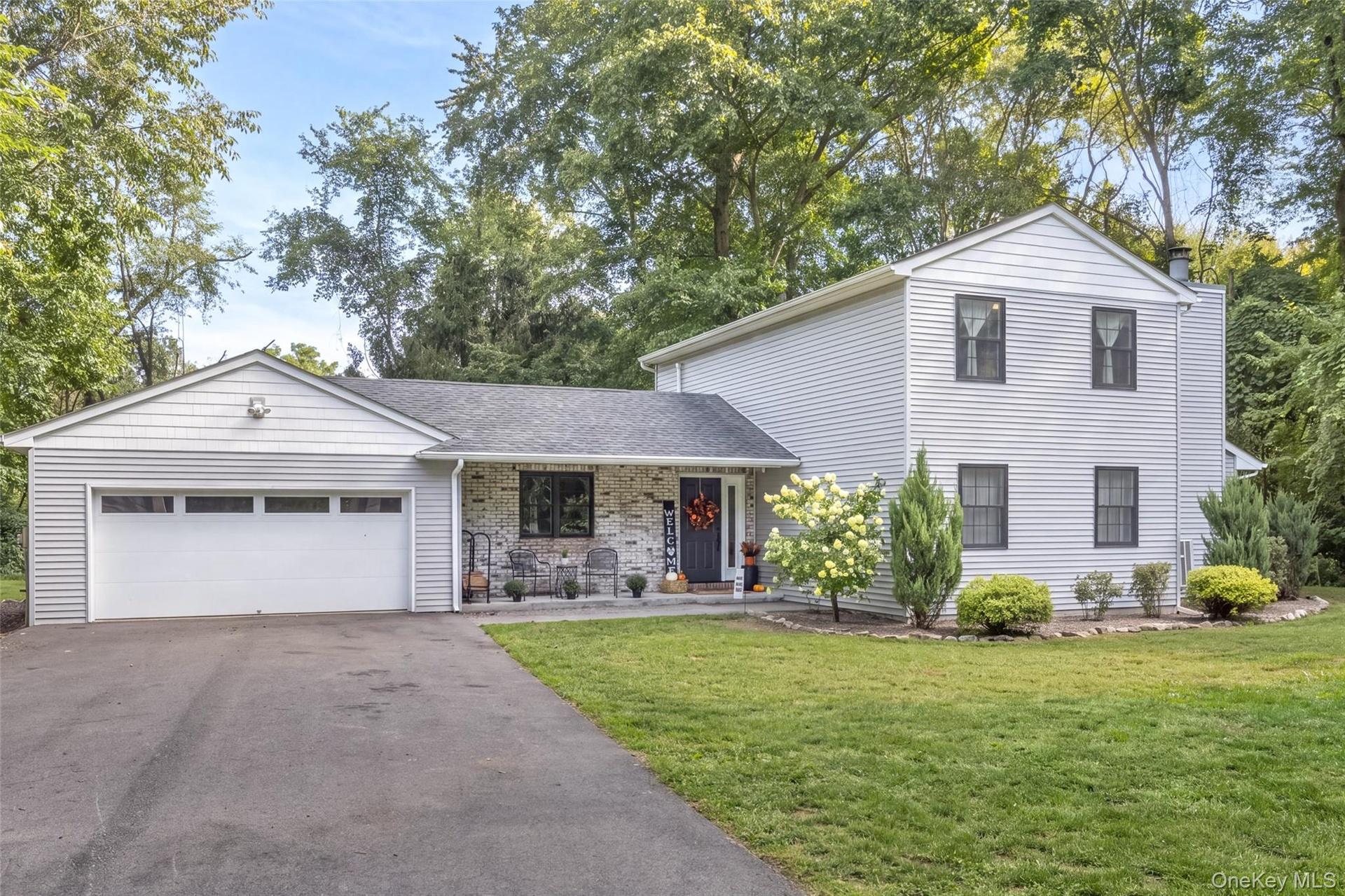 Two-story residence featuring light-colored siding, a two-car garage, and dark-trimmed windows