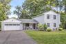 Two-story residence featuring light-colored siding, a two-car garage, and dark-trimmed windows