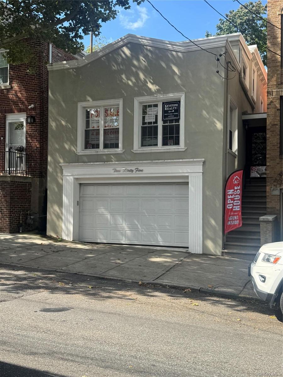 Stucco exterior with white trim, two upper-level and a two-car ground-level garage with a paneled door
