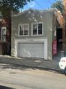 Stucco exterior with white trim, two upper-level and a two-car ground-level garage with a paneled door