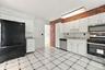 Kitchen featuring white cabinetry, a tile backsplash, stainless steel appliances, and a brick accent wall