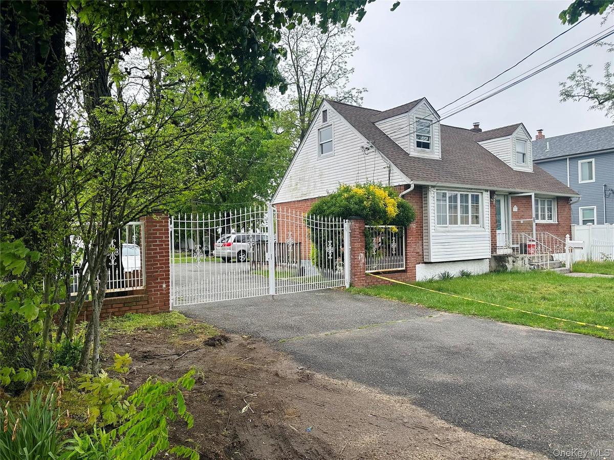 View of front of home with brick siding, a shingled roof, fence private yard, aphalt driveway, and a gate