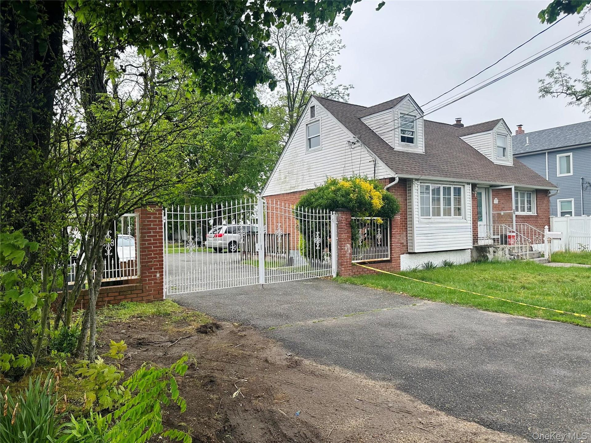 View of front of home with brick siding, a shingled roof, fence private yard, aphalt driveway, and a gate