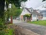 View of front of home with brick siding, a shingled roof, fence private yard, aphalt driveway, and a gate