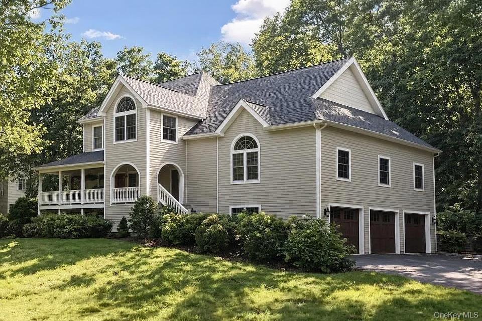 Front view of home featuring bluestone walkway, three-car garage and mature landscaping.AI generated pic to remove some of the trees.