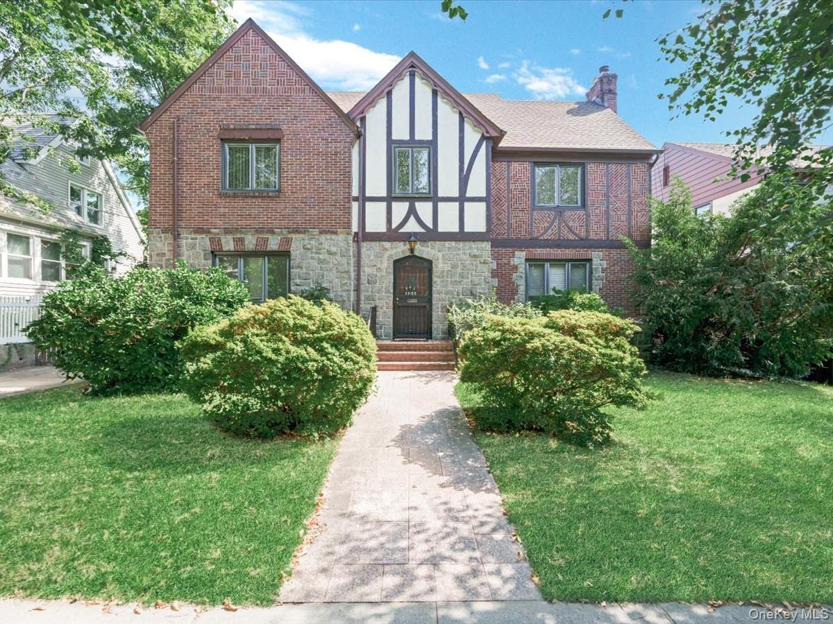 Tudor-style exterior featuring a stone and brick facade, a prominent gabled roofline, and a paved walkway leading to the entrance