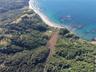 Aerial perspective of expansive coastal acreage featuring mature forested terrain, private shoreline access, and an inland pond