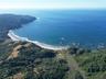 Coastal property featuring direct shoreline access, expansive sandy beach, and surrounding natural topography with dense wooded terrain and inland wat