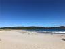 Coastal shoreline featuring a sandy beach, rolling hills, and ocean surf