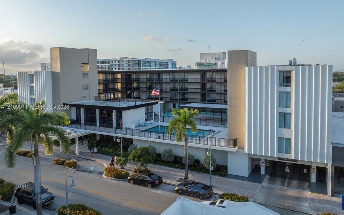 Mid-century modern architectural exterior featuring ribbed concrete facades, multi-story open-air corridors, an elevated swimming pool, and on-site pa