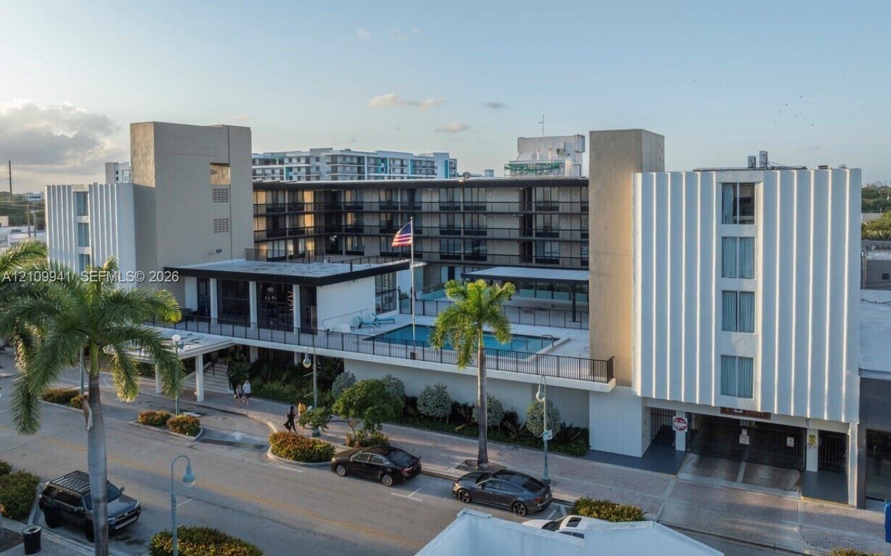 Mid-century modern architectural exterior featuring ribbed concrete facades, multi-story open-air corridors, an elevated swimming pool, and on-site pa
