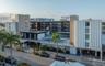 Mid-century modern architectural exterior featuring ribbed concrete facades, multi-story open-air corridors, an elevated swimming pool, and on-site pa