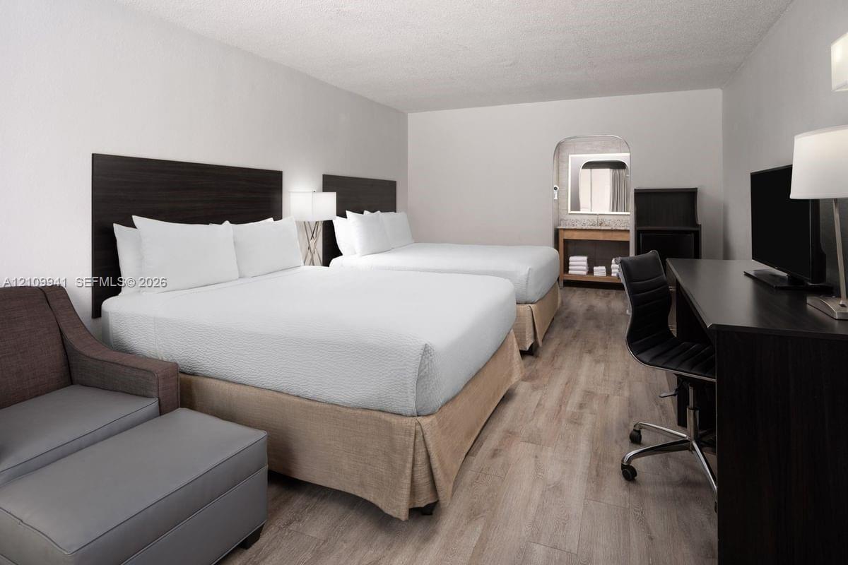 Wood-finish flooring, dark-toned wall-mounted headboards, and a built-in vanity area with a mirror