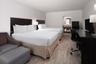 Wood-finish flooring, dark-toned wall-mounted headboards, and a built-in vanity area with a mirror