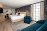 Wood-finish flooring, grid-pattern glass block window, wall-mounted air conditioning unit, and built-in kitchenette cabinetry