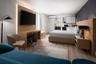 Wood-finish flooring, custom wood-paneled accent wall with integrated lighting, built-in desk, cabinetry with integrated kitchenette, and wall-mounted