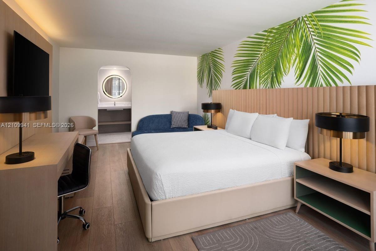 Vertical slat wood headboard, wood-finish flooring, custom built-in wood-finish workstation, and archway with recessed lighting and circular vanity mi
