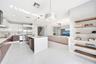 Modern kitchen featuring high-gloss cabinetry, a central island with quartz countertop, stainless steel appliances, polished tile flooring, and integr