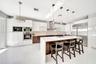 Contemporary kitchen featuring high-gloss cabinetry, a central island with a solid surface countertop, stainless steel appliances, and pendant lightin