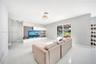 Open-concept living space featuring high-gloss tile flooring, recessed lighting, built-in media cabinetry with floating shelving, and sliding glass do