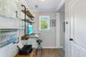 Built-in industrial-style shelving with wood-finish surfaces, wall-mounted desk, crown molding, and wood-finish flooring