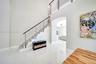 High-ceiling foyer featuring polished large-format tile flooring, a staircase with custom horizontal metal balusters, a dark wood handrail, and a rece