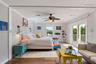 Living space featuring wood-finish flooring, a ceiling fan with integrated lighting, wall-mounted light fixtures, and glass sliding doors providing ac