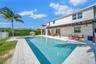 Backyard featuring a custom swimming pool, a raised tiled spa, a covered pergola, and paved decking