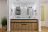 Double vanity featuring a stone-surface countertop, dual rectangular sinks with matte black faucets, light wood-finish cabinetry with linear pulls, an