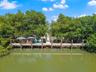 Private dock featuring wood-plank decking and anchored pilings, surrounded by mature trees