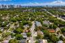 Aerial perspective of property featuring a rectangular pool, concrete paver patio, and mature trees on the lot