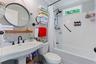 Bright, updated bathroom featuring a curved pedestal sink with matte black fixtures, subway tile shower surround with glass enclosure, circular mirror