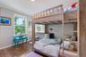 Bedroom featuring wood-finish flooring, a large window with exterior greenery, and a built-in wall-mounted shelf