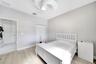Room featuring wood-finish flooring, textured wall covering, bi-fold closet doors, and a multi-blade ceiling fan with integrated lighting
