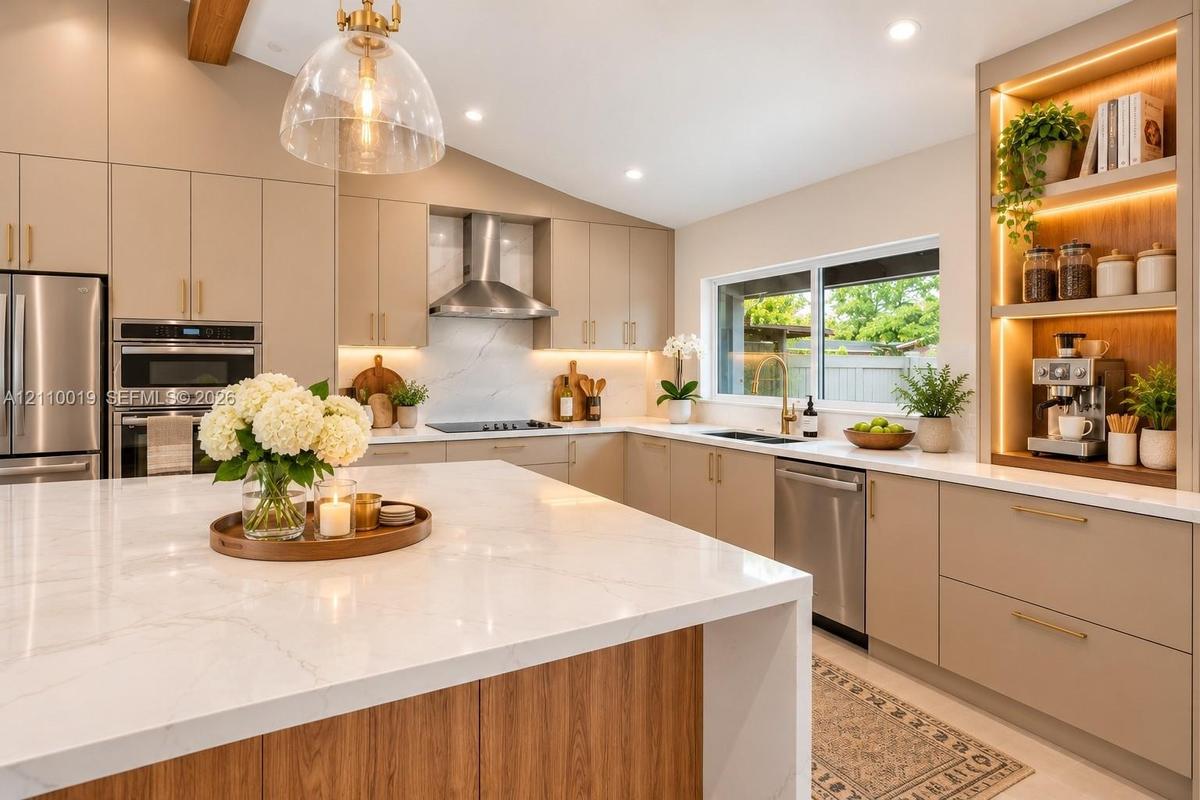 Kitchen featuring an oversized waterfall island with stone countertop, flat-panel cabinetry, stainless steel appliances, a built-in illuminated displa