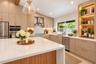 Kitchen featuring an oversized waterfall island with stone countertop, flat-panel cabinetry, stainless steel appliances, a built-in illuminated displa