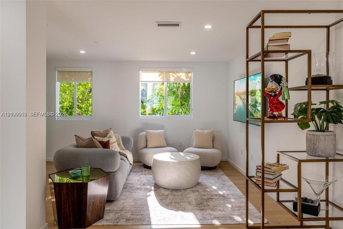 Living area featuring recessed lighting, dual windows with integrated shades, and wood-finish flooring
