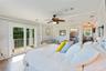 Room featuring wood-finish flooring, a ceiling fan with integrated lighting, glass sliding doors opening to an exterior balcony, crown molding, and an